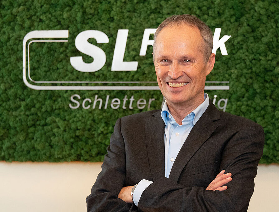 [Translate to Spanish:] Portrait Ludwig Schletter vor Mooswand mit SL Rack Logo