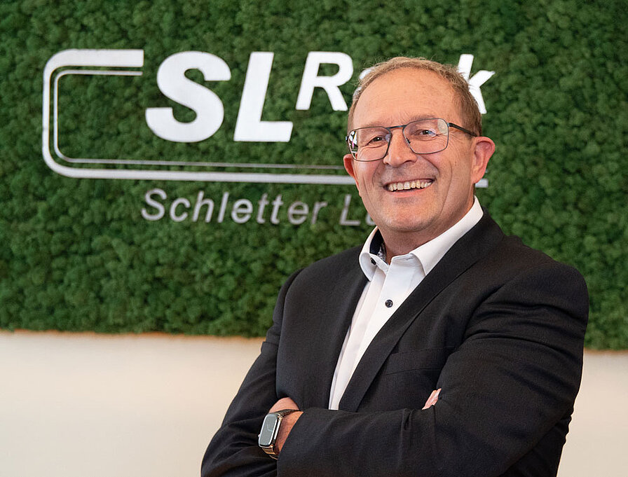 [Translate to Spanish:] Portrait Georg Bauer vor Mooswand mit SL Rack Logo